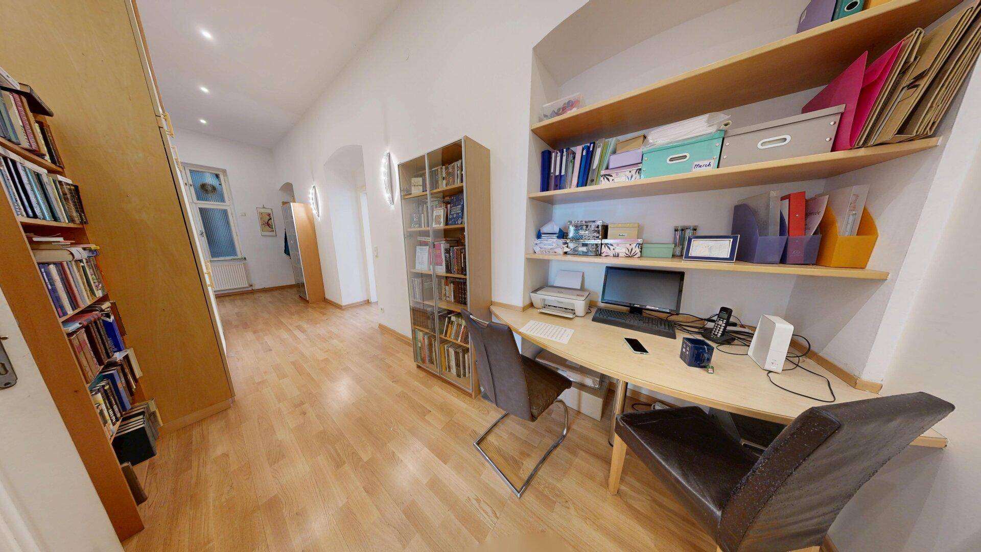 Arbeitsbereich im Flur mit Schreibtisch, Regalen und Bücherwänden, ideal für Home-Office.