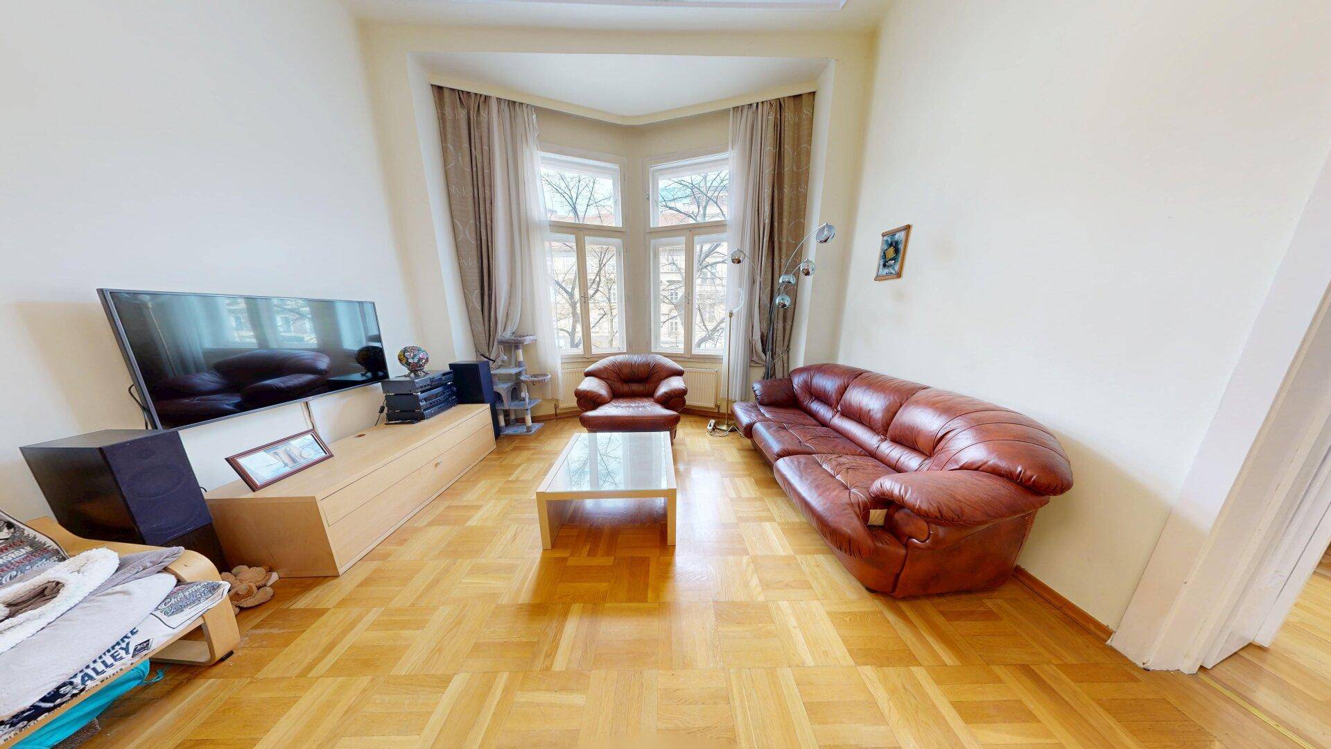 Gemütliches Wohnzimmer mit Ledersofa, Sessel, TV-Möbel und einem Erkerfenster für viel Licht.