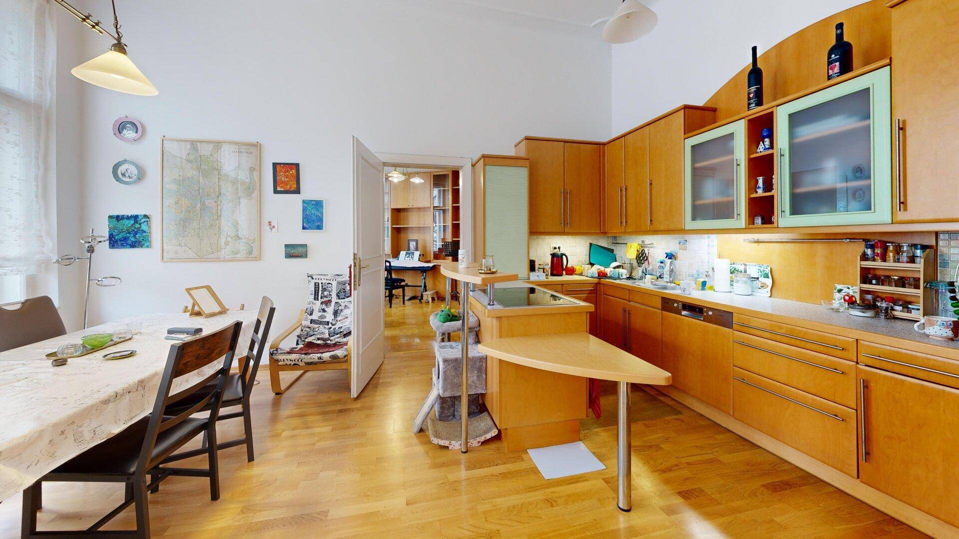Offene Wohnküche mit Holzmöbeln, Essbereich und Durchgang zu einem weiteren Zimmer.