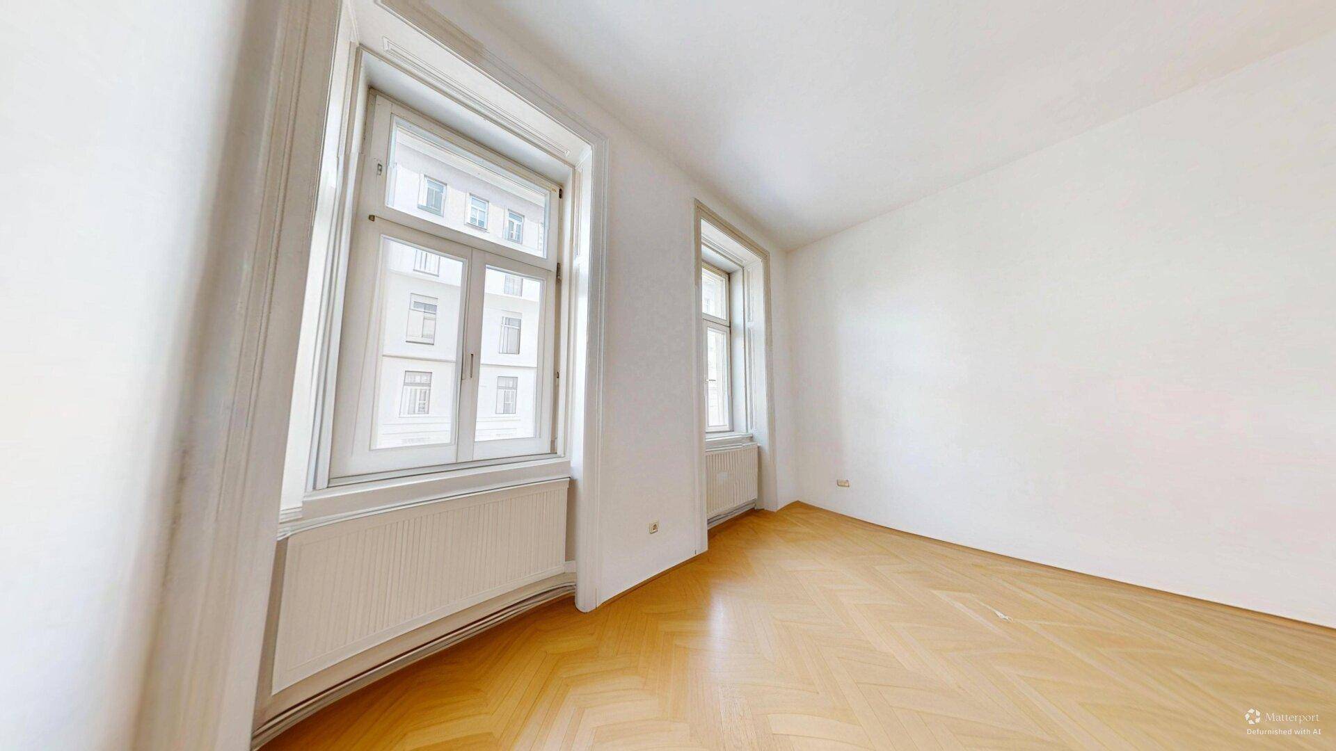 Geräumiges, helles Zimmer mit Fischgrätparkett und zwei hohen Fenstern, vielseitig nutzbar.