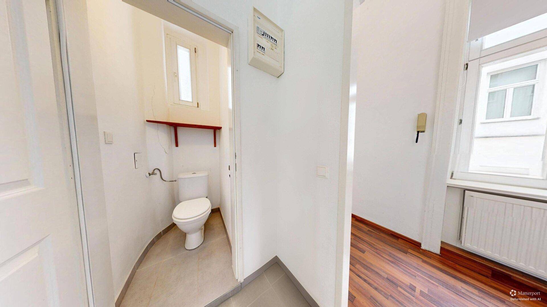 Kleiner Toilettenraum mit WC, kleinem Fenster und Ablagefläche, direkt vom Flur zugänglich.