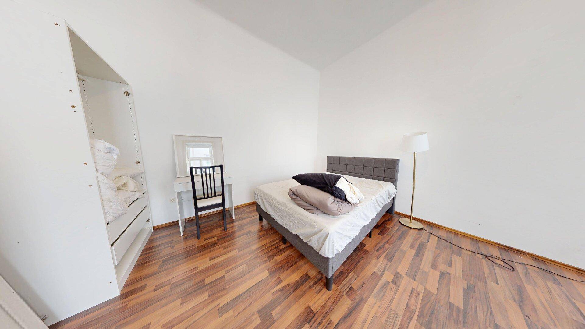 Gemütliches Schlafzimmer mit Bett, Schminktisch und Kleiderschrank, ausgestattet mit warmem Holzboden.