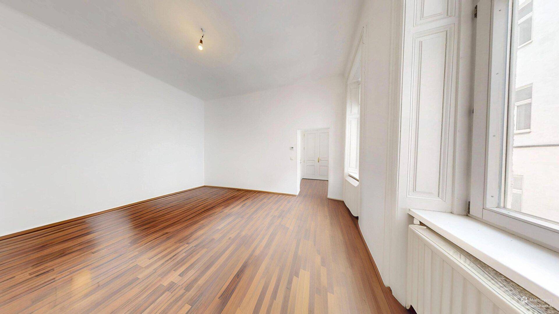 Geräumiges, helles Zimmer mit Holzboden und weißen Wänden, bereit für individuelle Einrichtungsideen.