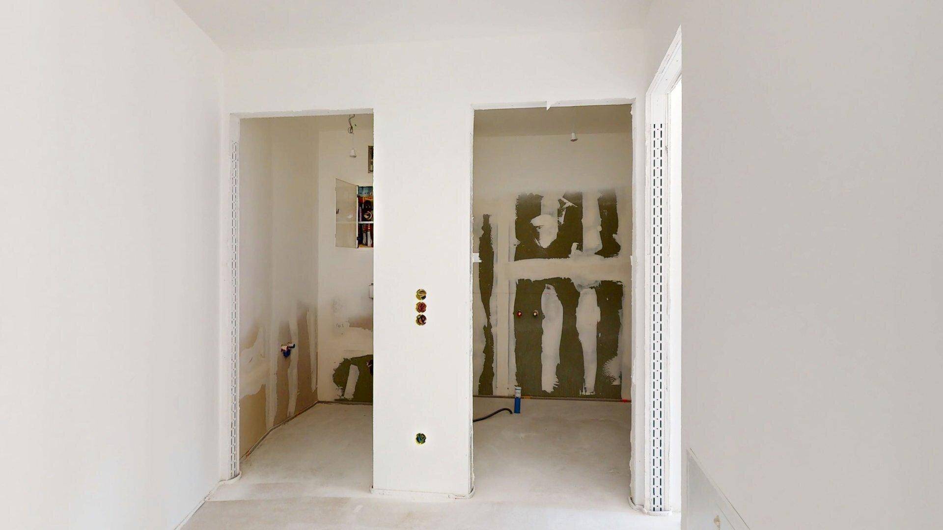Zwei offene Räume im Rohbauzustand mit sichtbaren Installationen, bereit für den weiteren Ausbau.