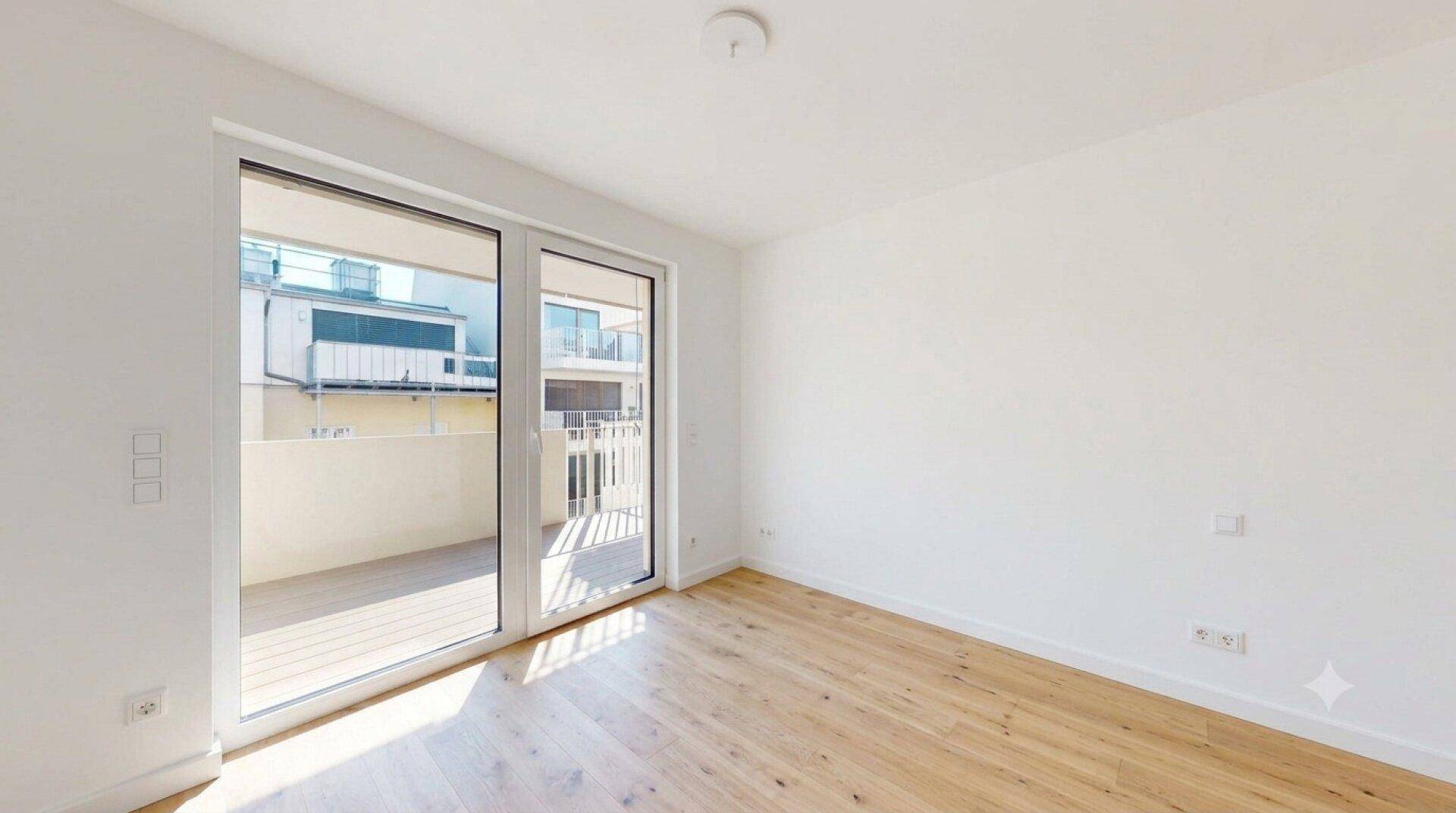Freundlicher Raum mit Holzboden und zwei großen Glastüren, die den Zugang zum Balkon ermöglichen.