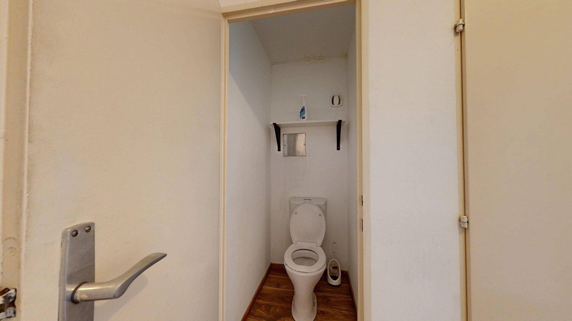 Kleines, funktionales WC mit Toilette und Ablagefläche, ideal für Gäste.