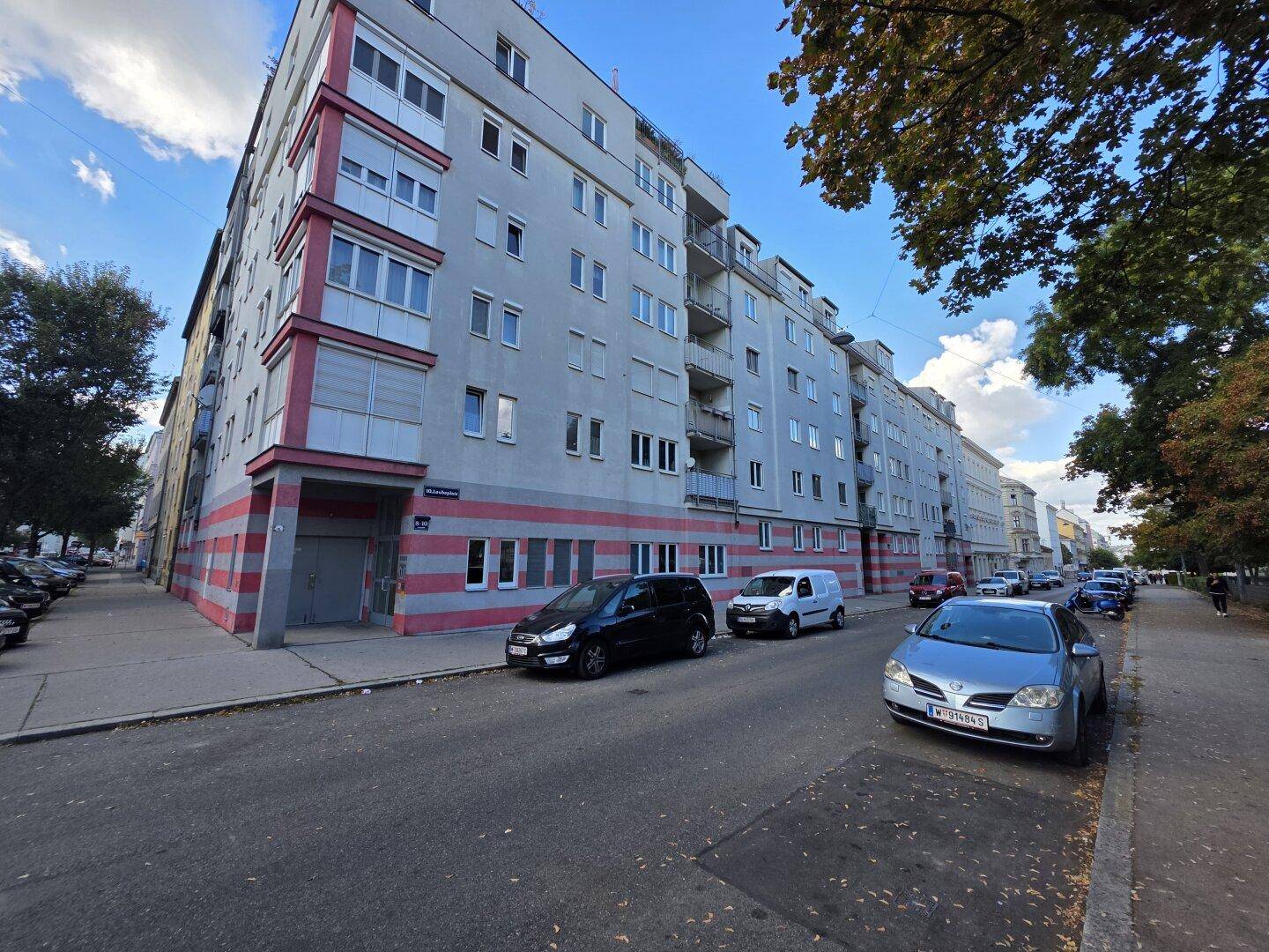 Mehrfamilienhaus mit moderner Fassade und Balkonen an einer städtischen Straße.