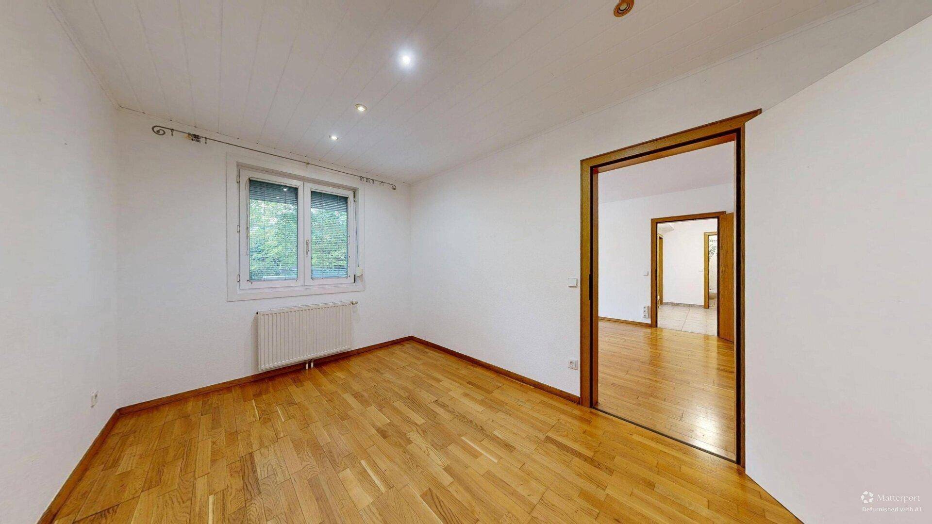 Helles Zimmer mit Parkettboden, weißen Wänden und Deckenstrahlern, ideal als Schlafzimmer.