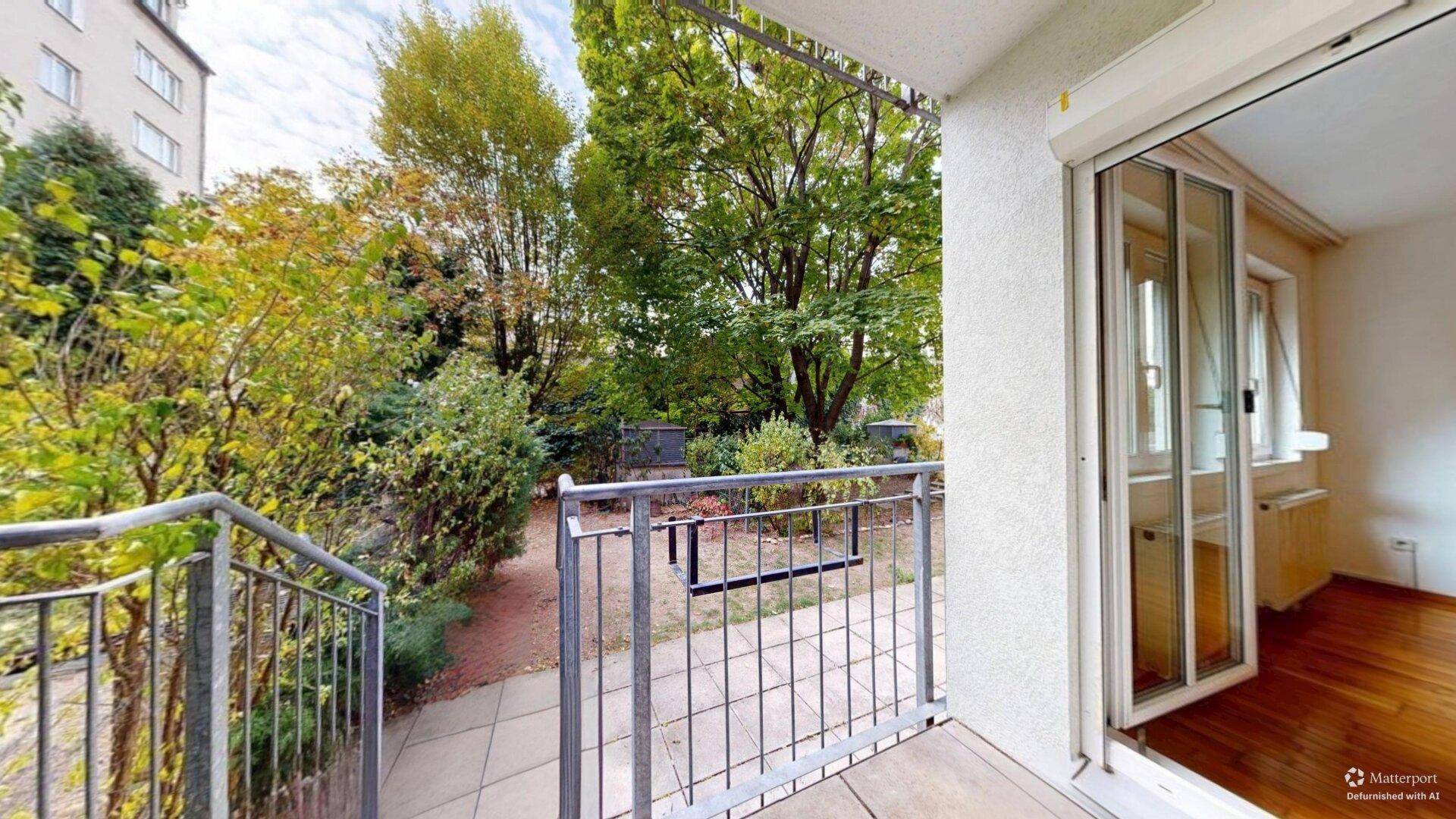 Balkon mit Blick auf den Garten und Zugang zu einem hellen Innenraum mit Holzfußboden.