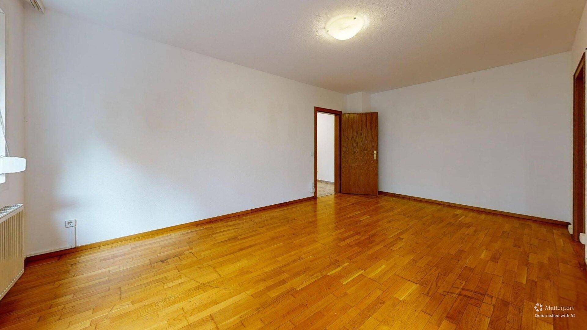 Leeres Zimmer mit hellem Parkettboden und weißen Wänden, bereit zur individuellen Gestaltung.