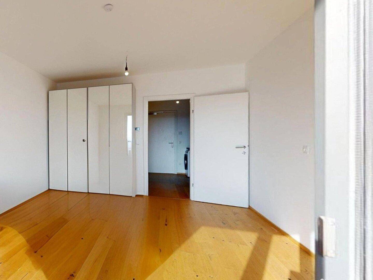 Helles Zimmer mit Holzboden und weißem Kleiderschrank, ideal als Schlafzimmer oder Büro.