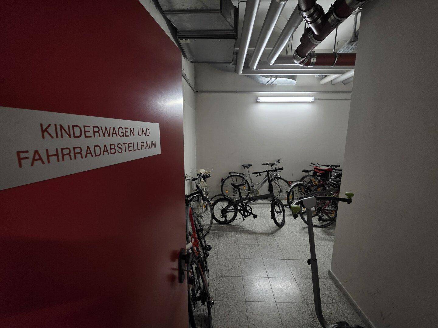 Gemeinschaftlicher Abstellraum für Kinderwagen und Fahrräder, gut beleuchtet und zugänglich.