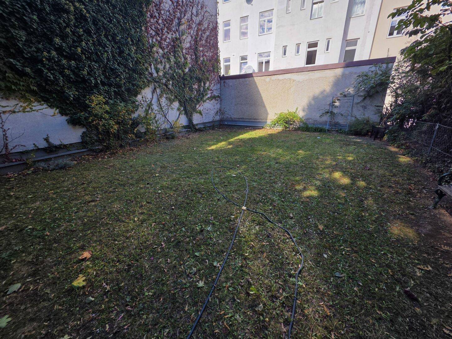 Grüner Gartenbereich mit Rasenfläche und umgebenden Mauern, ideal zur Entspannung im Freien.