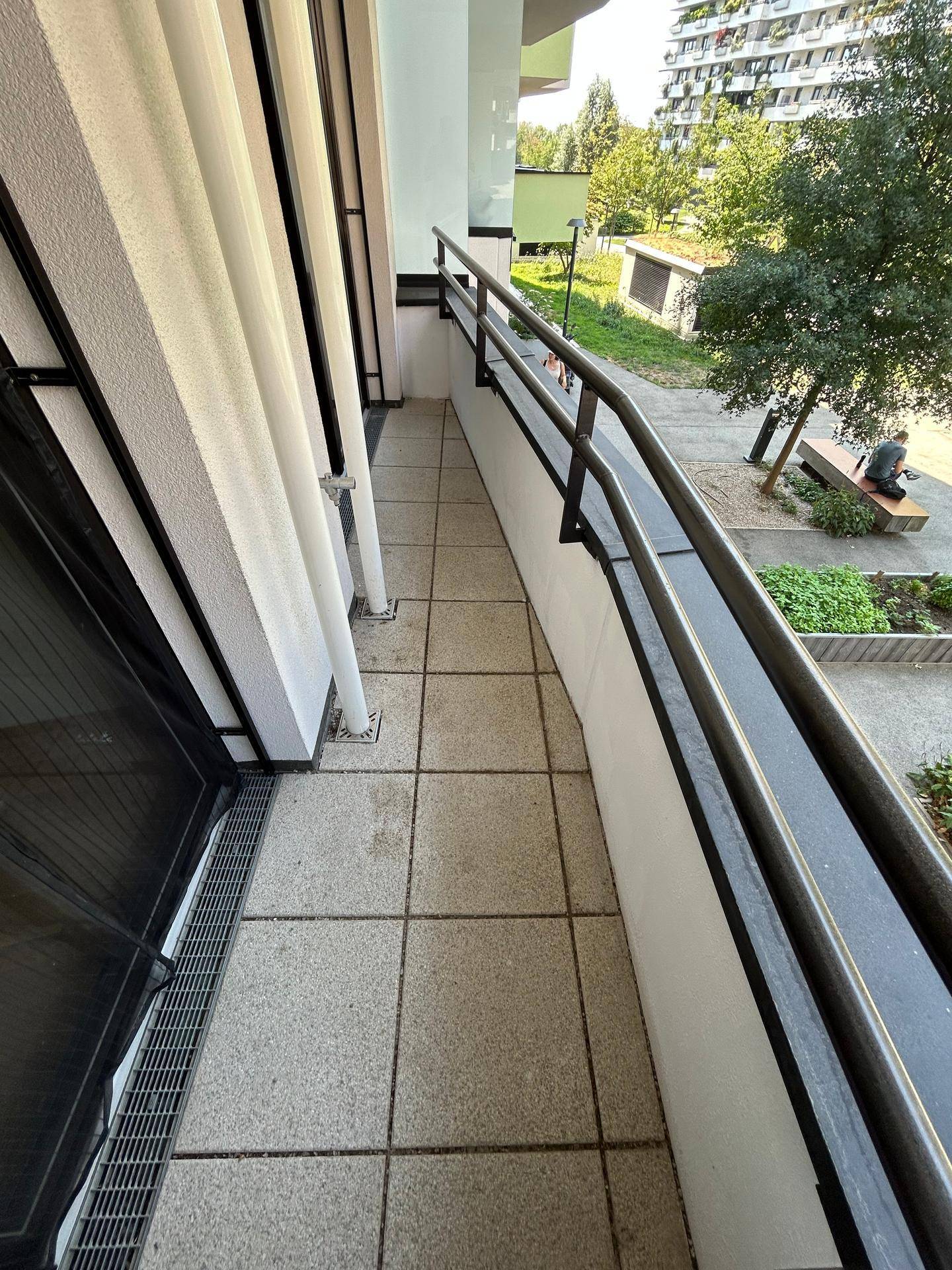Schmaler Balkon mit Fliesenboden und Metallgeländer, bietet Blick auf die Umgebung.