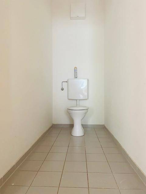 Separates WC mit Fliesenboden und einfacher Toilette.