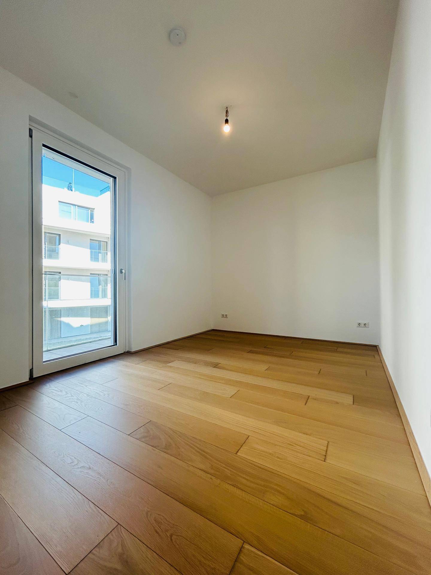 Helles Schlafzimmer mit Holzboden und direktem Zugang zu einem Außenbereich.