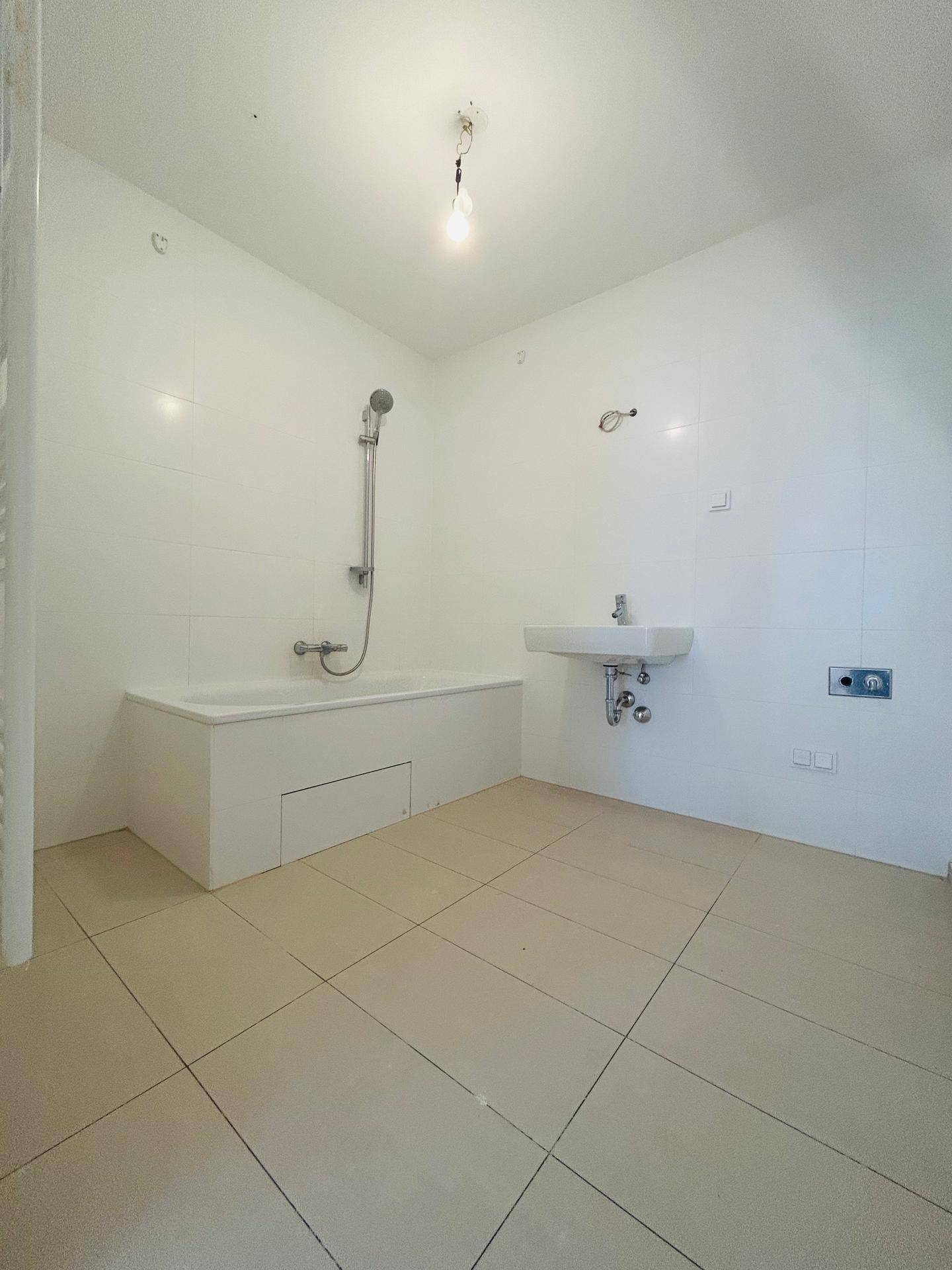 Modernes Badezimmer mit Badewanne, Dusche und hellen Fliesen, in neuwertigem Zustand.