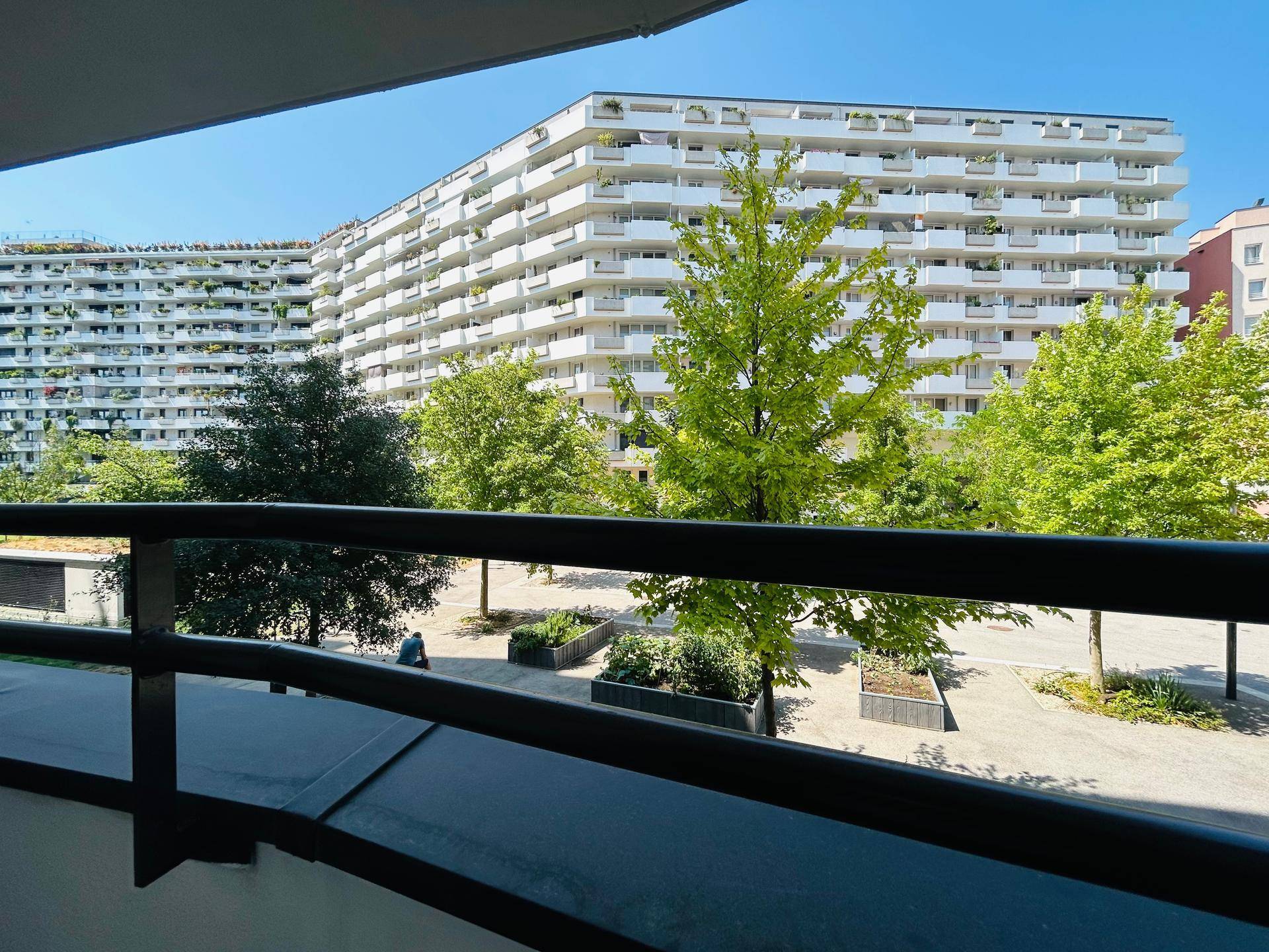 Weitblick von einem Balkon auf weitere moderne Wohngebäude und einen begrünten Innenhof.