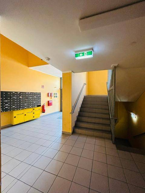 Heller Eingangsbereich eines Mehrfamilienhauses mit Treppenhaus und Briefkästen.
