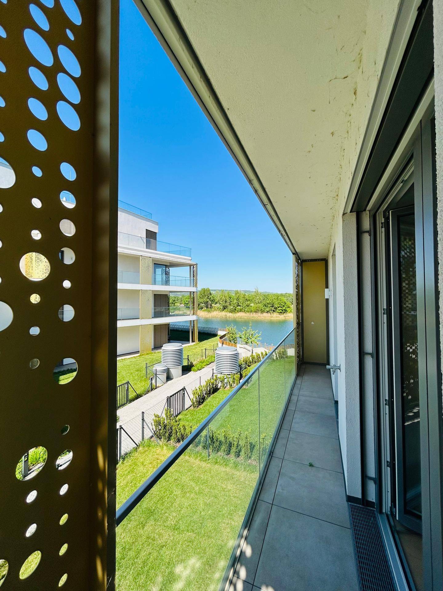 Balkon mit weitem Blick auf einen See und die umliegende grüne Landschaft.