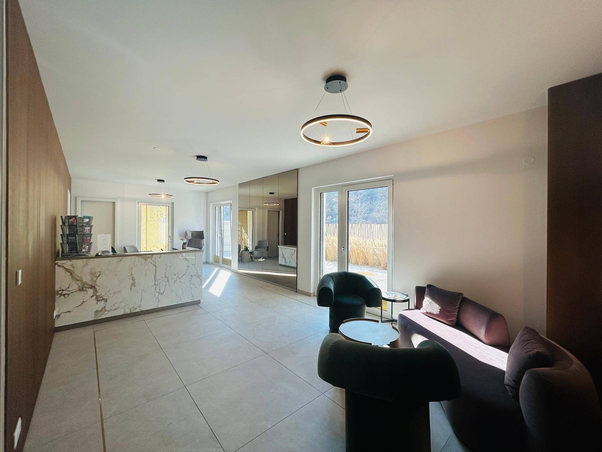 Elegante Lobby mit Marmor-Rezeption, modernen Sitzgelegenheiten und viel Tageslicht.