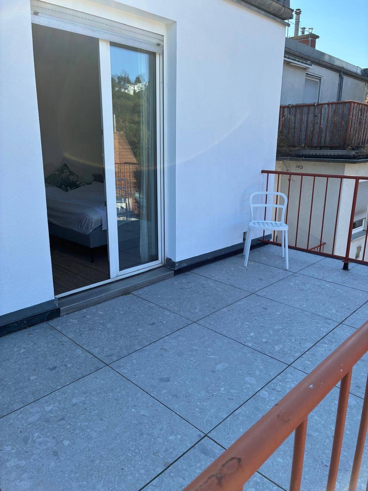 Terrasse mit Fliesenboden und Schiebetür, die Zugang zu einem Innenraum bietet.