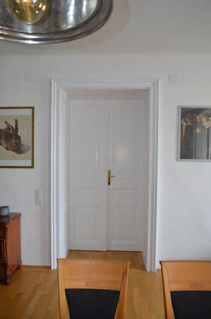 Weiße Doppeltür mit klassischem Design, die zu einem weiteren Raum führt.