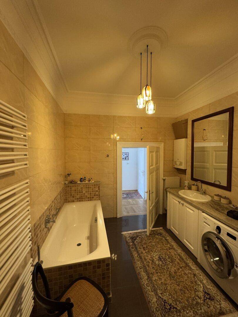 Geräumiges Badezimmer mit Badewanne, Waschmaschine und gelben Fliesen.