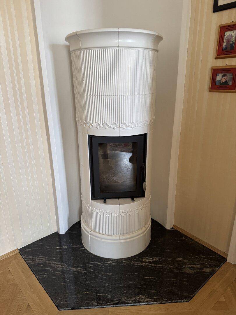 Traditioneller Kachelofen in einer Ecke des Raumes mit dunklem Granitboden.