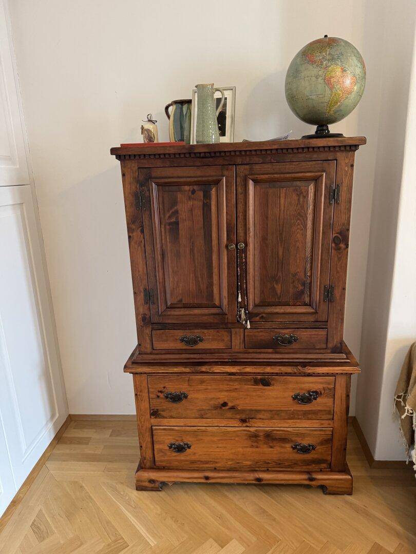 Rustikaler Holzschrank mit Schubladen und einem Globus als Dekoration.