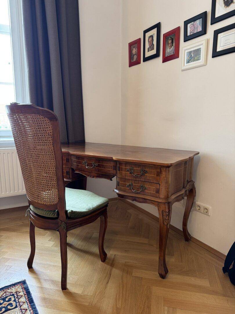 Antiker Schreibtisch mit Stuhl in einem hellen Raum mit Fischgrätparkett.