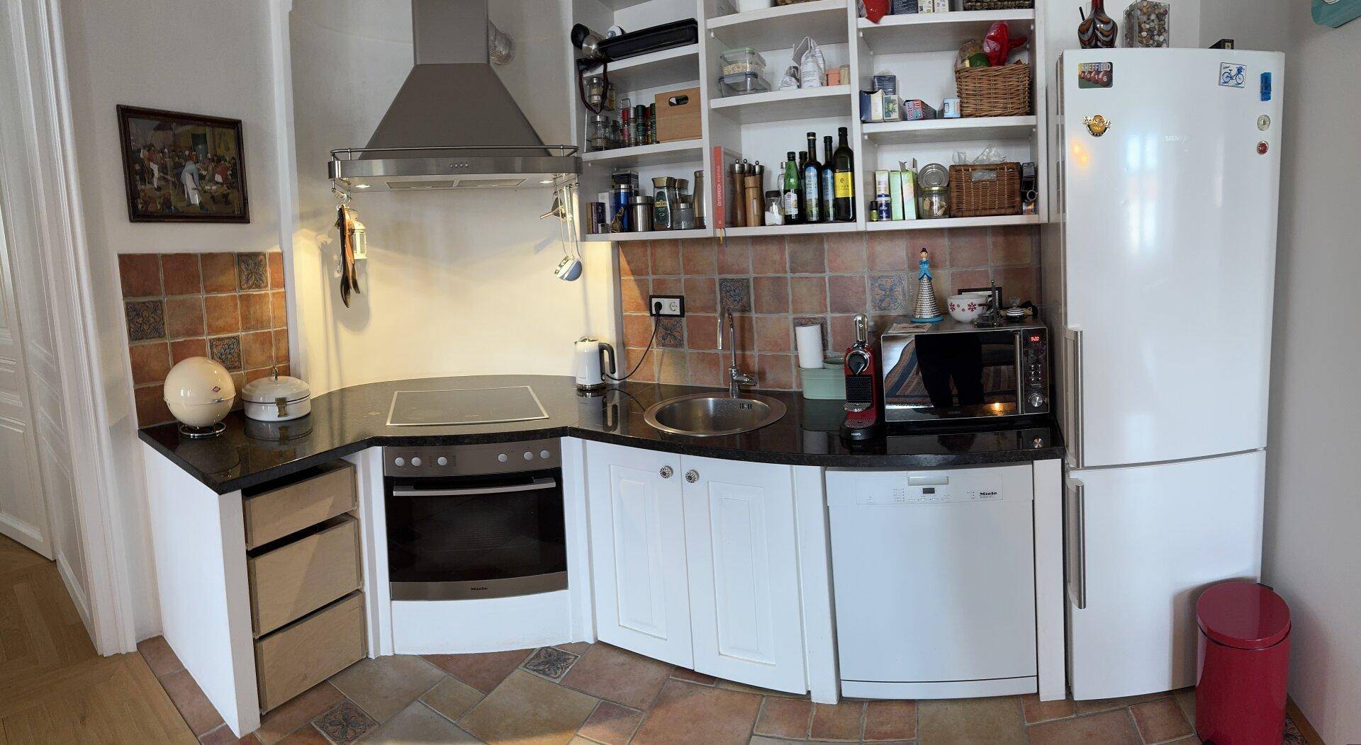 Funktionale Küche mit weißen Schränken, Fliesenrückwand und integrierten Geräten.