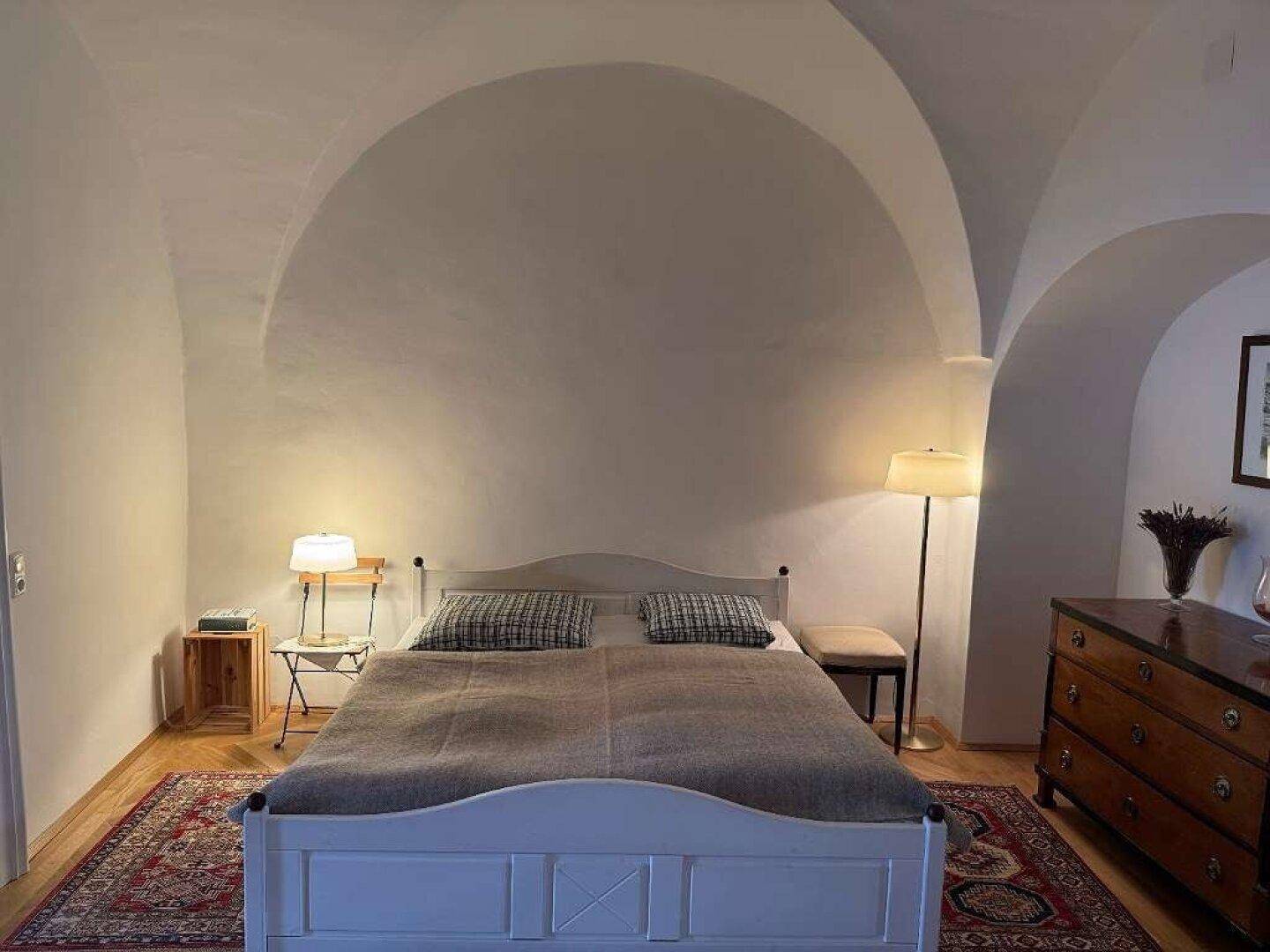 Schlafzimmer mit Gewölbedecke, Holzboden und einem gemütlichen Doppelbett.