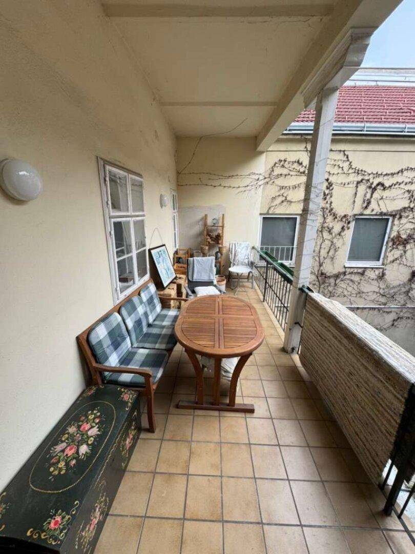 Langer Balkon mit Sitzgelegenheiten und Blick auf den Innenhof.