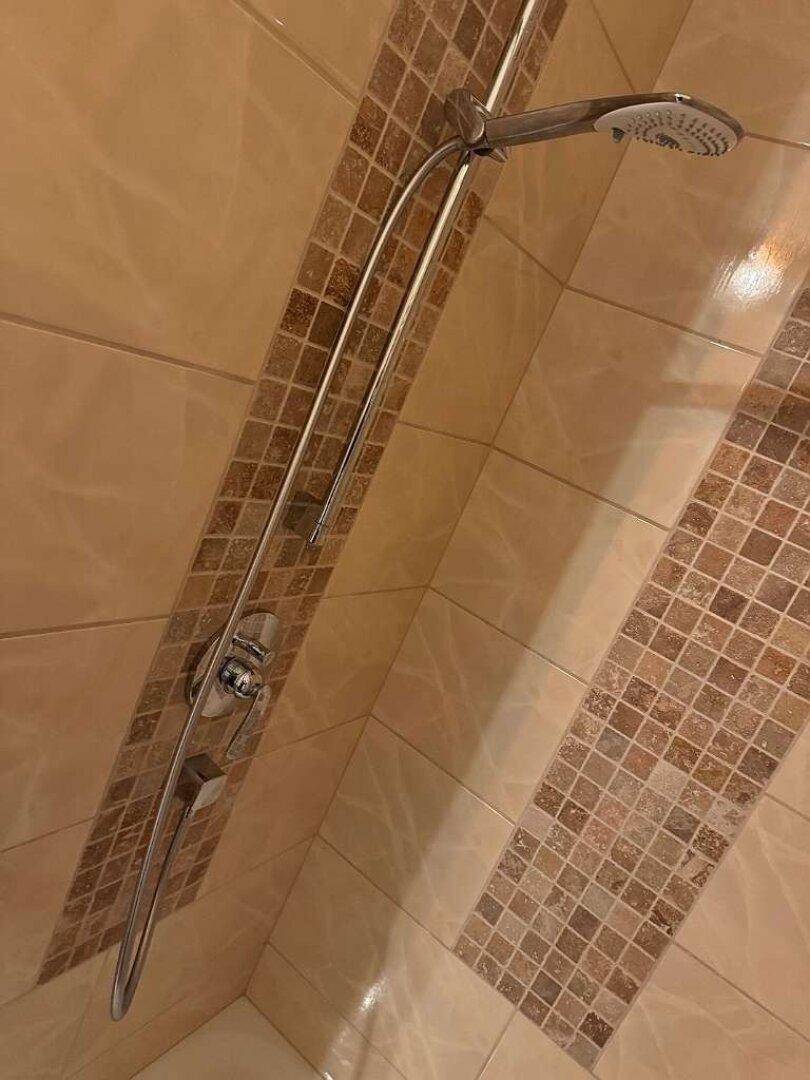 Duschbereich mit beigen Fliesen und einer modernen Duscharmatur.