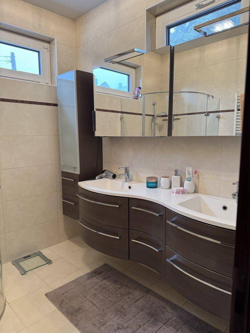 Modernes Badezimmer mit Doppelwaschbecken, Spiegelschrank und Fliesenboden.