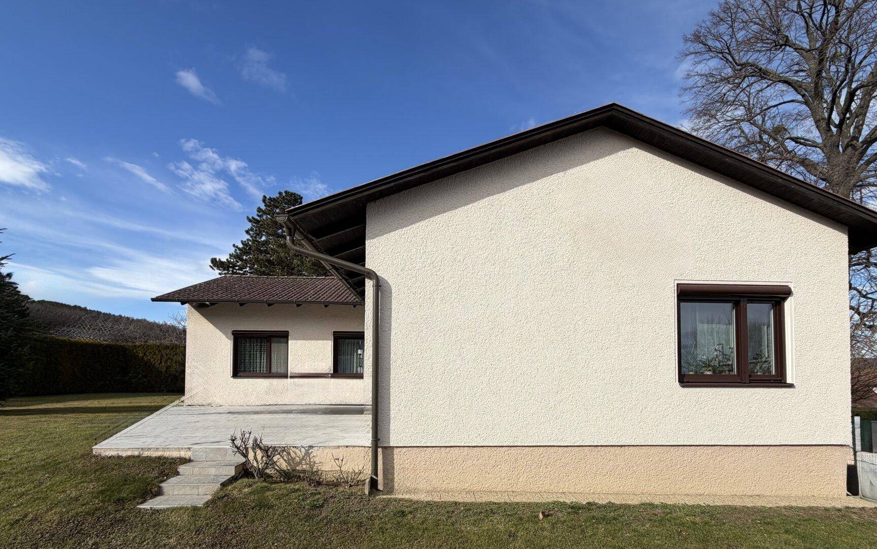 Seitenansicht des Hauses mit Rasenfläche und Blick auf die umliegende Landschaft.
