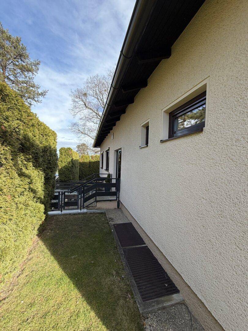 Seitenbereich des Hauses mit Treppe und gepflegter Hecke entlang des Grundstücks.