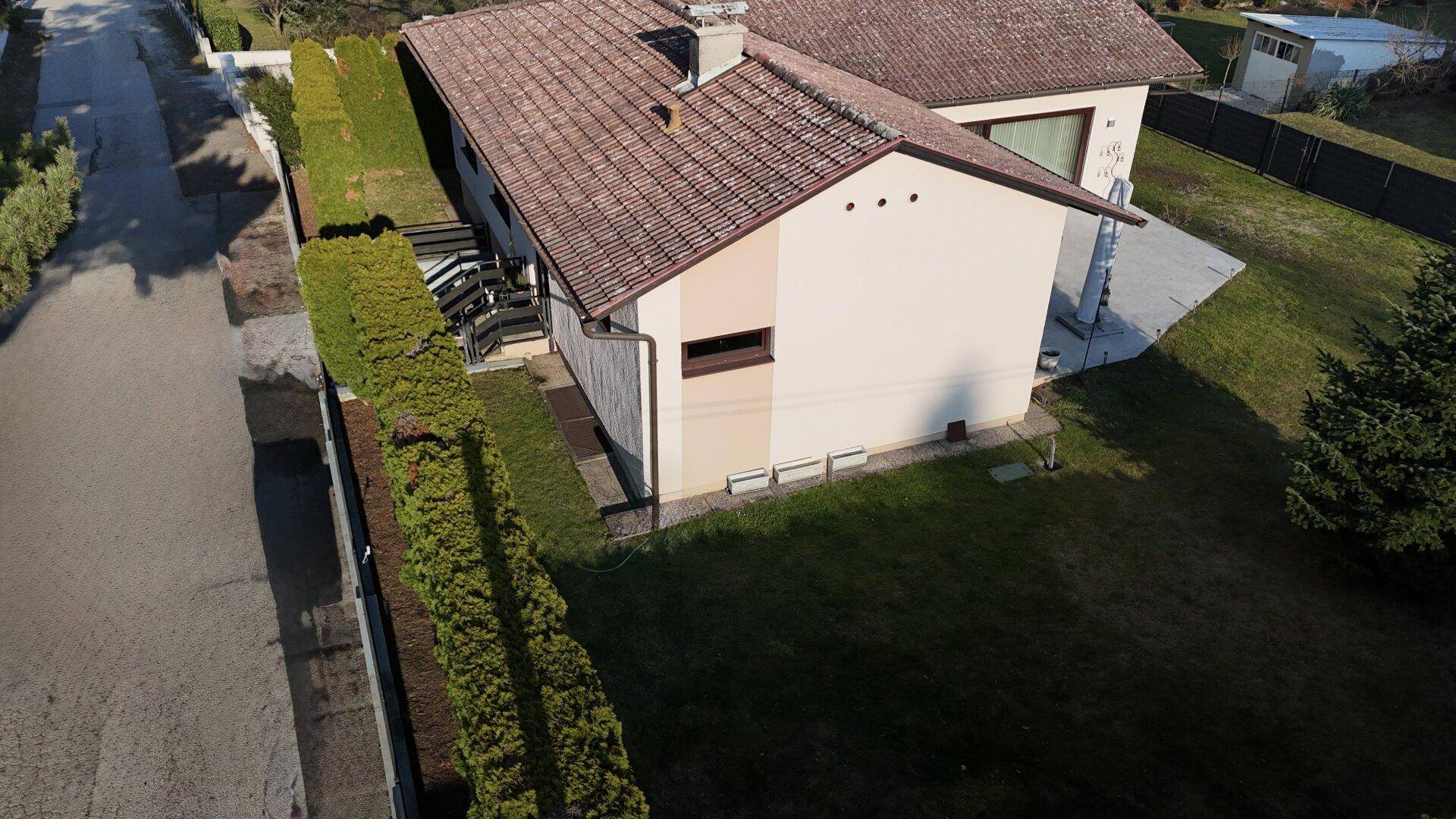 Luftaufnahme des Hauses mit Garten, Terrasse und Zufahrt von oben.