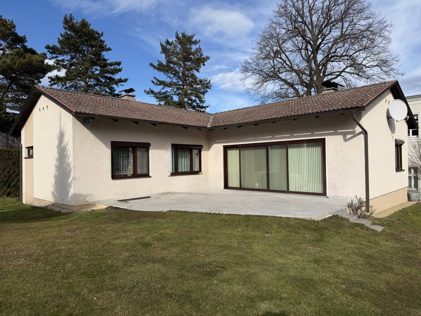 Hinterhof mit großer gepflasterter Terrasse und Rasenfläche, ideal für Entspannung.