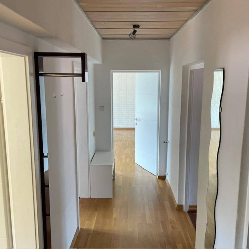 Heller Flur mit Holzboden, Holzdecke und Garderobe.