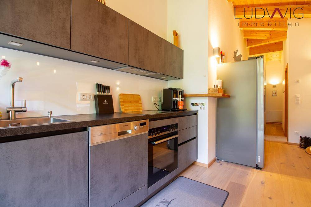 Moderne Einbauküche mit grauen Fronten, integrierten Geräten und großem Kühlschrank.