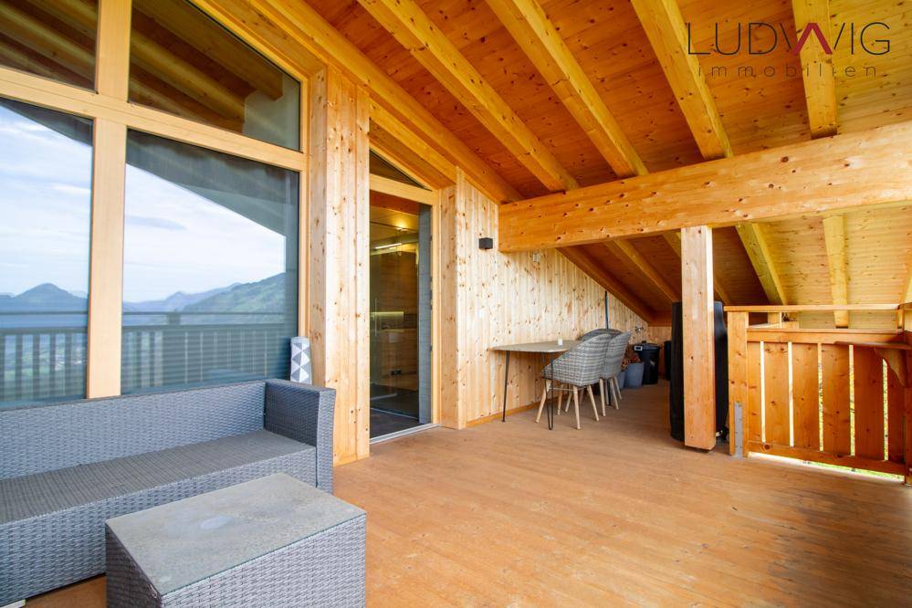 Großer Holzbalkon mit Sitzgelegenheiten und Panoramablick auf die umliegenden Berge.