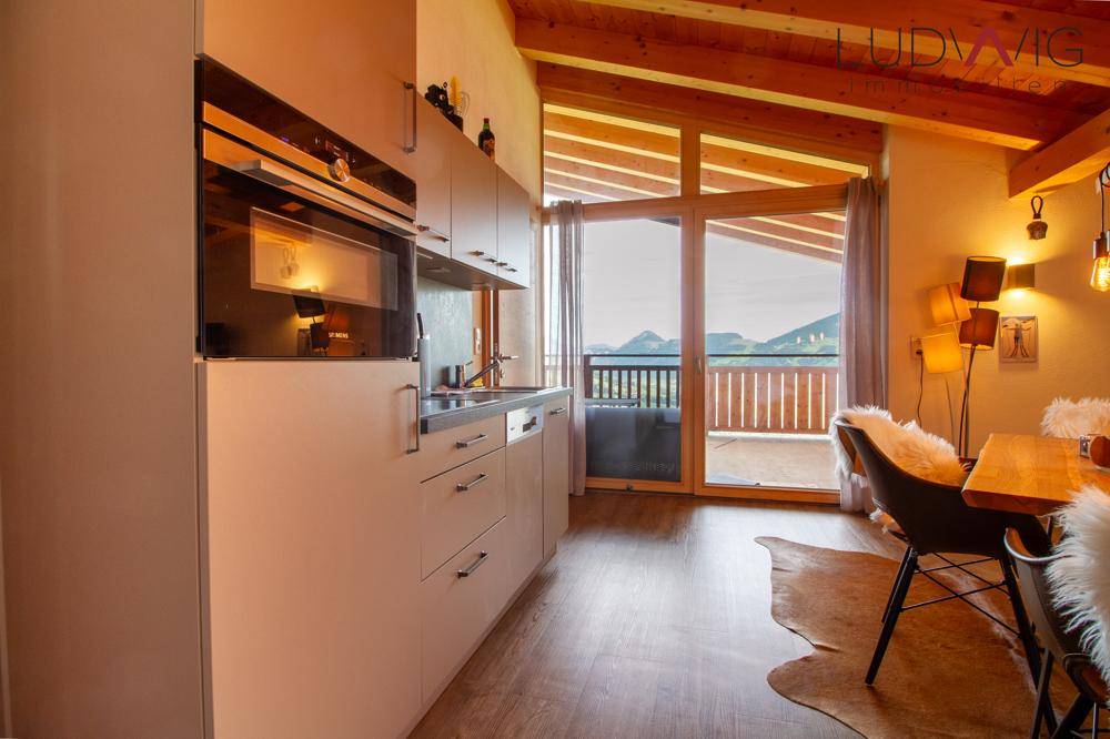Moderne Küche mit integrierten Geräten und Balkonzugang, bietet einen schönen Blick auf die Berge.
