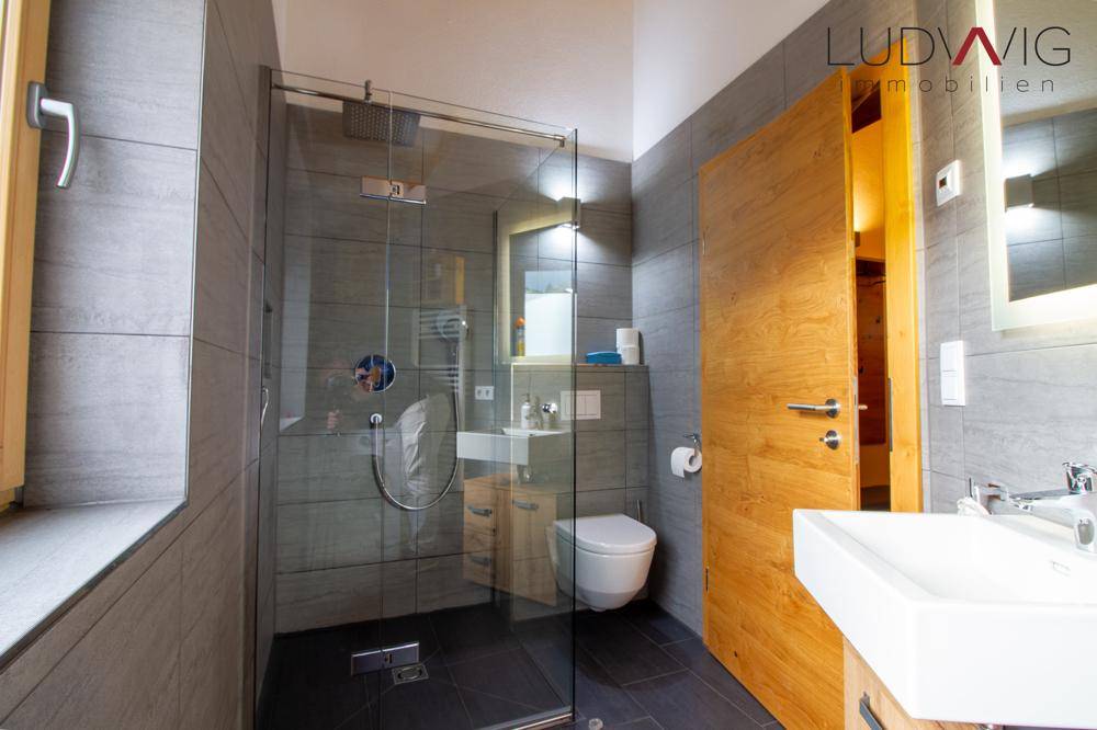 Modernes Badezimmer mit begehbarer Dusche, Fenster und stilvollen grauen Fliesen.