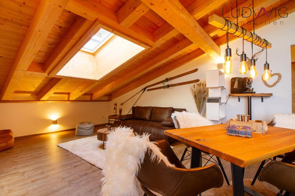 Gemütlicher Wohnbereich unter dem Dach mit Holzbalken, Dachfenster und rustikalem Charme.