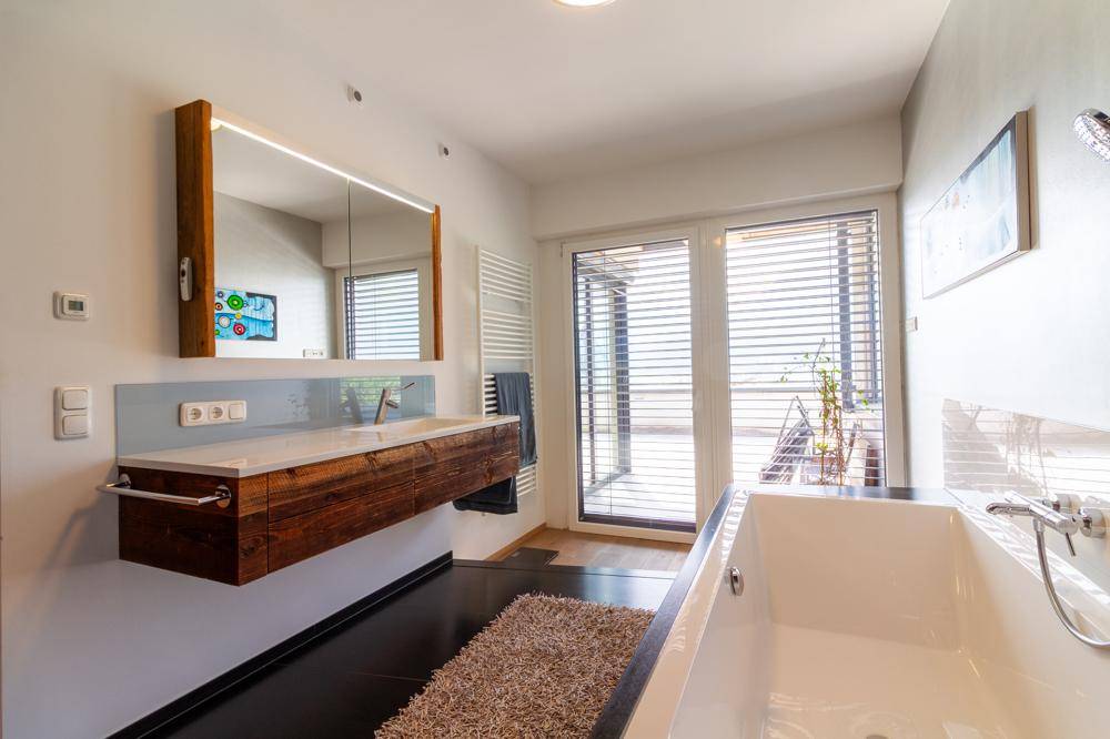 Elegantes Badezimmer mit schwebendem Holzwaschtisch, Spiegel und Badewanne.