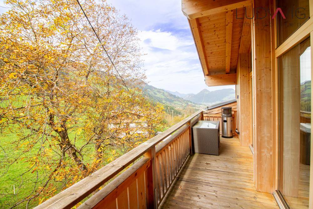 Großer Holzbalkon mit Bergblick und herbstlicher Vegetation, ideal zum Entspannen im Freien.