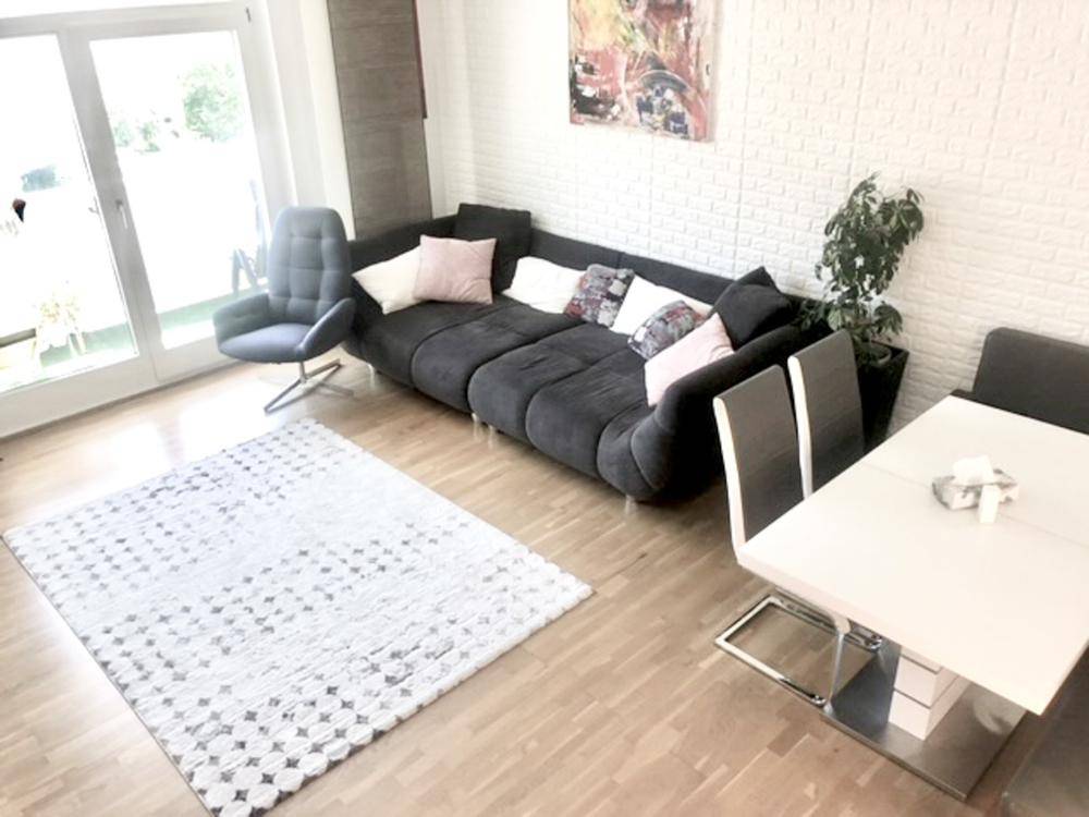 Geräumiger Wohn-Essbereich mit Holzboden, bequemer Couch und Zugang zur Terrasse.