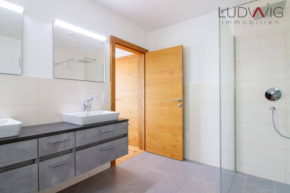 Modernes Badezimmer mit Doppelwaschtisch, großem Spiegel und begehbarer Dusche.